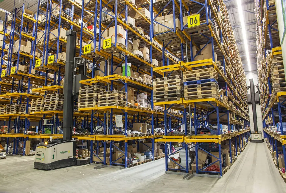 Narrow aisle between high bay pallet racking in a working distribution warehouse